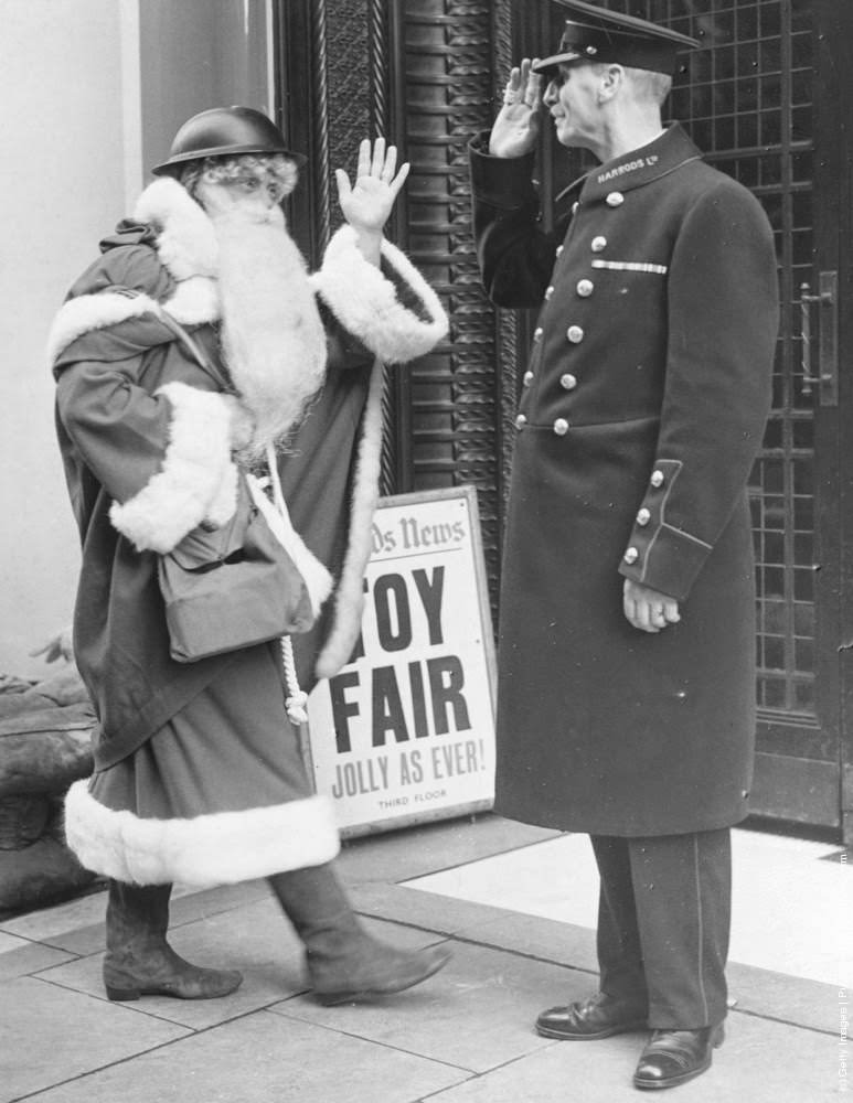 Even Father Christmas follows the war time safety precautions as he arrives this year, complete with tin helmet and gas mask case, at London's famous Brompton road store, Harrods. 6th November 1939.