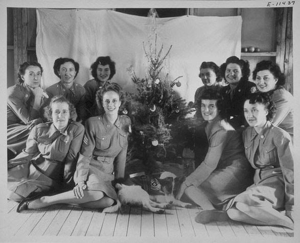 Shown are WACs of the 2nd War Company, Norfolk Air Base, Barracks A, HRPE, seated around a Christmas tree with their mascot dog.
