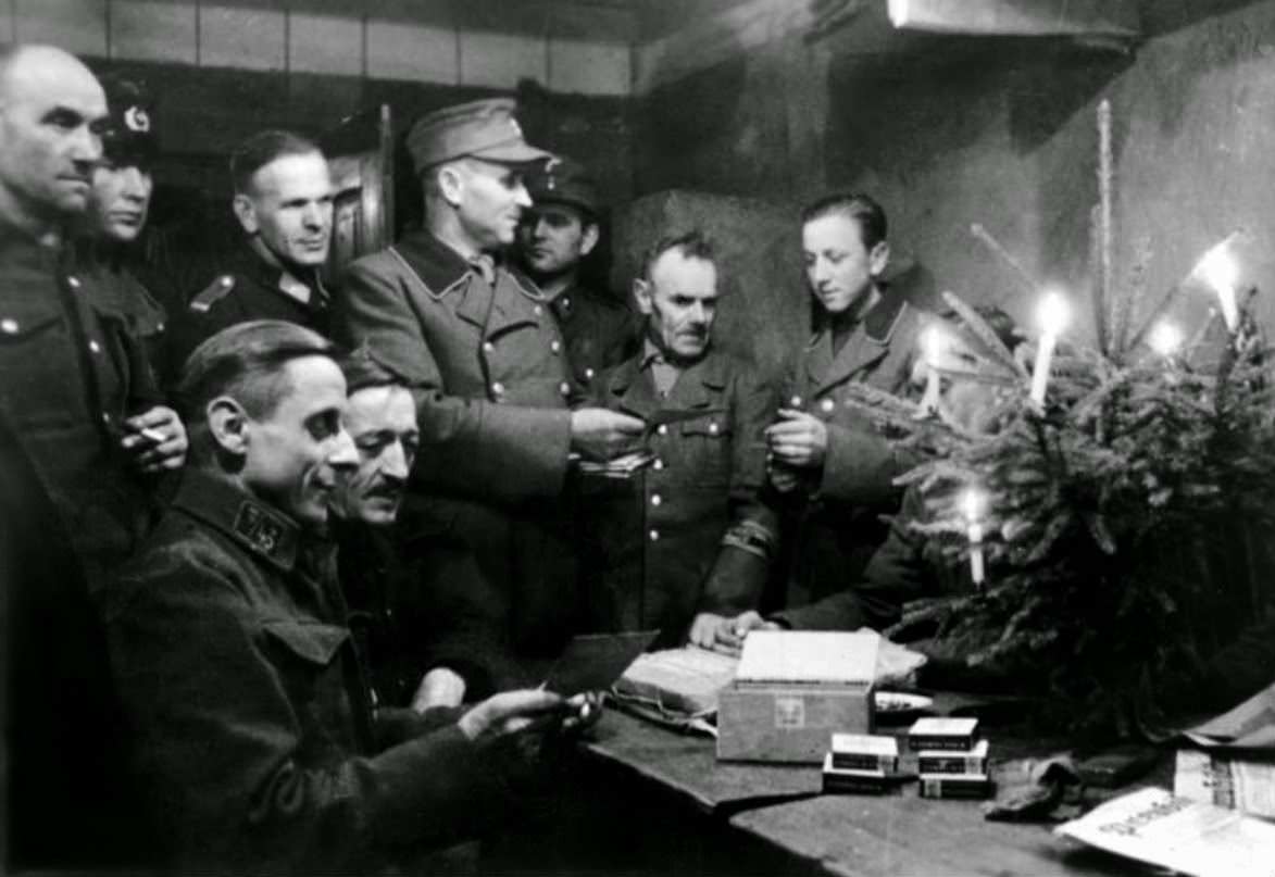 German soldiers of the Volkssturm celebrate Christmas in a cellar, sharing with each other cigarettes and holiday messages from home delivered on postcards. The Volkssturm was established on 18 October 1944.