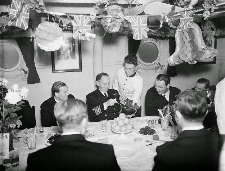 The Captain of HMS MALAYA helping himself to plum pudding during Christmas dinner at Scapa Flow, 25 December 1942.