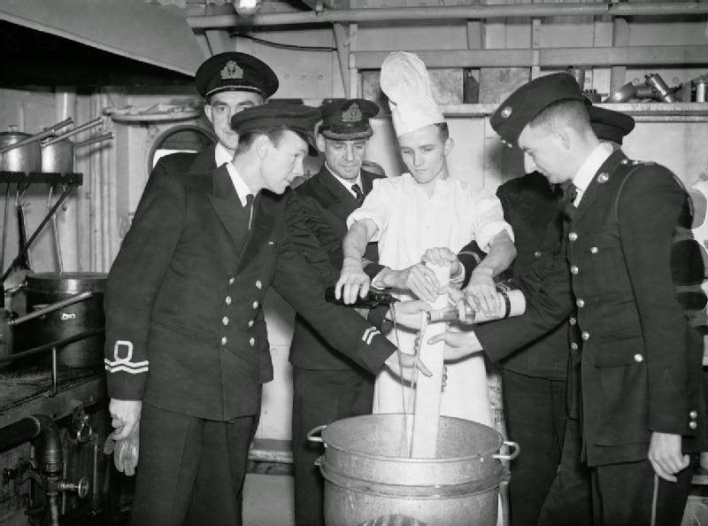 The officers and wardroom cook mixing the Christmas Pudding on board HMS HOWE.