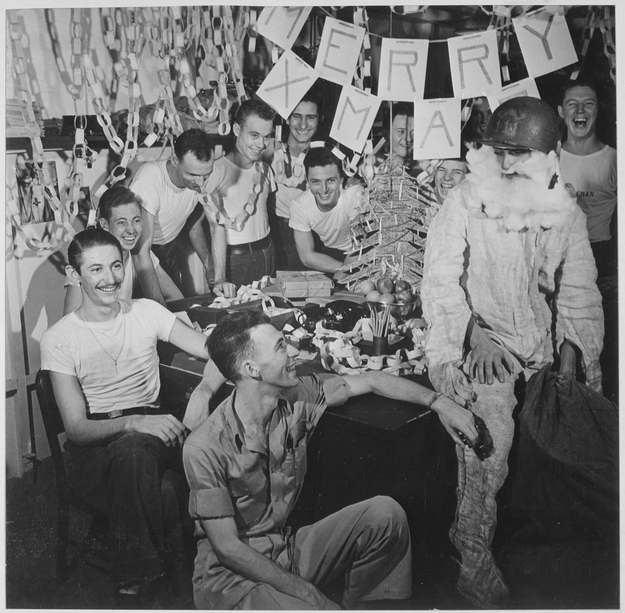 Men of the USS Lexington celebrating Christmas with a Santa suited up for firefighting. 1944.