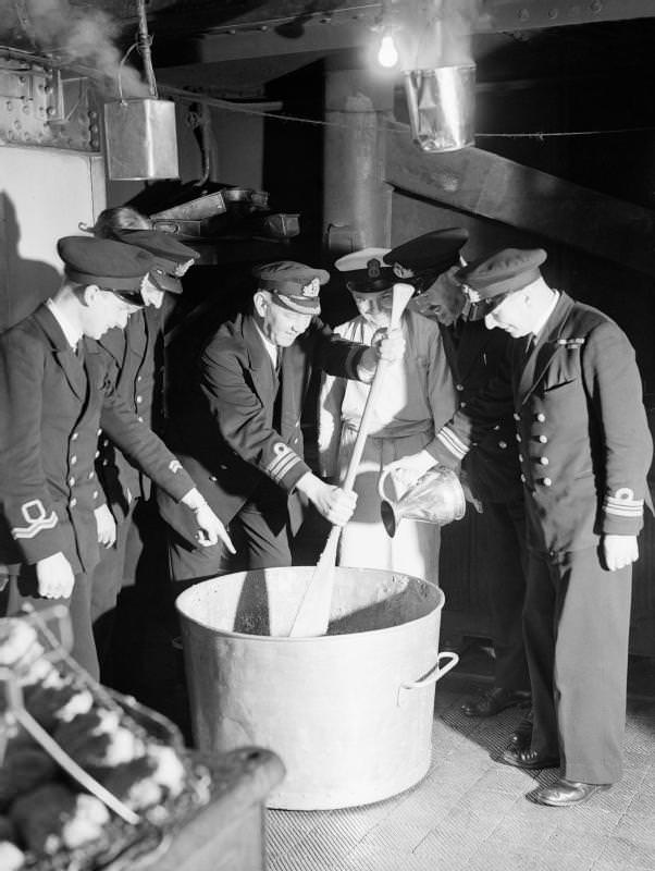 The Brits, of course, had to have their Christmas pudding. The commander of a destroyer stirs the pudding, while the first lieutenant adds rum, 1942.