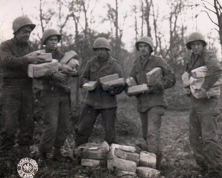 US Army Pfc. W. J. Kessler, Pfc. J. L. Proffitt, Pvt. B. Narter, Cpl. T. J. Barnewski, and Pfc. J. Stoll handling Christmas packages from home for their artillery unit, Germany, 26 Nov 1944.
