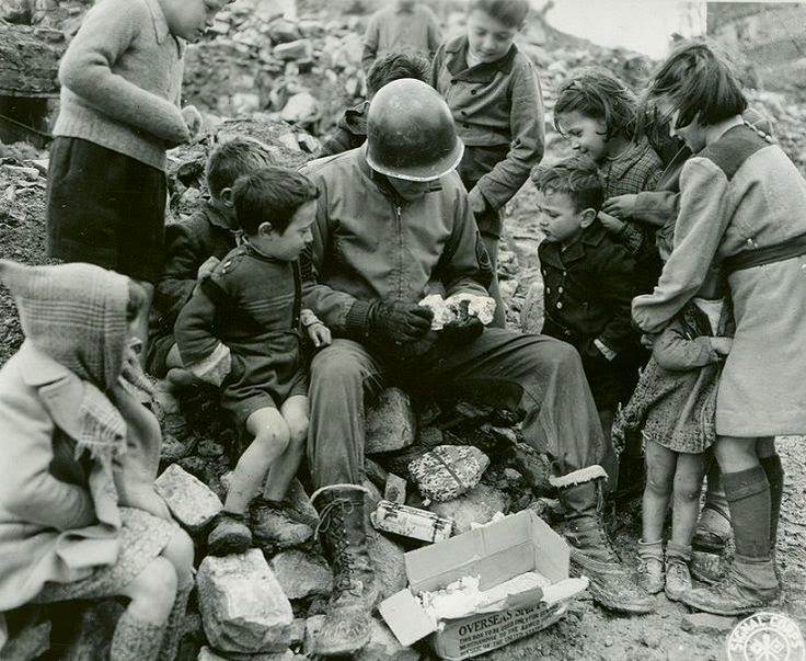 An American soldier shares presents from home with Italian children during Christmas.