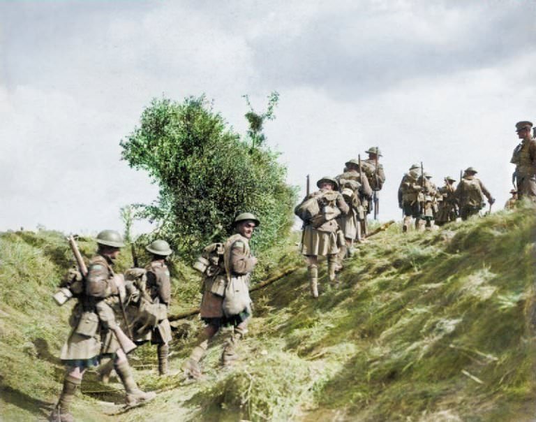Scottish troops march with combat gear and rifles slung over their backs as they make their way over a grassy mound during the Battle of the Canal du Nord, 1918.