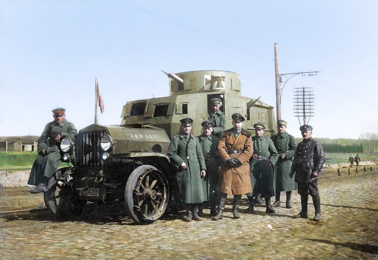German officers with an armored car, Ukraine, Spring of 1918. They stand next to the car as they smile for the camera.