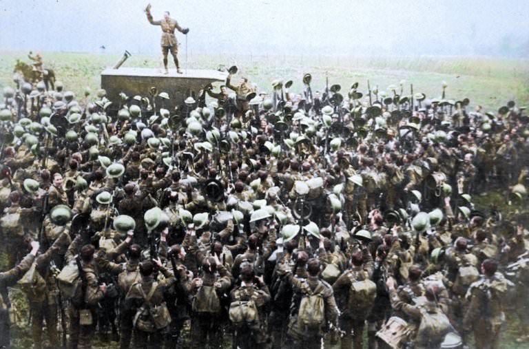 A crowd of soldiers on the Western Front celebrating as an officer announces the news of the Armistice.