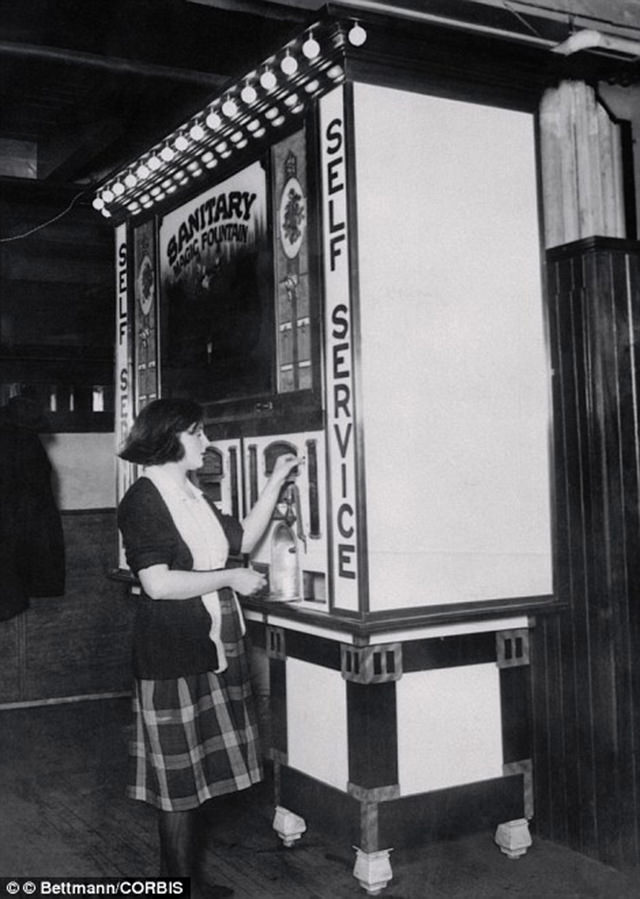 A woman uses The Maiwarm Company soda machine in 1928. It was the first of its kind not to require a soda squirter.