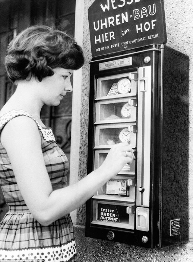 A woman in Berlin, Germany uses a coin-operated device to buy a clock, ca. 1960s.