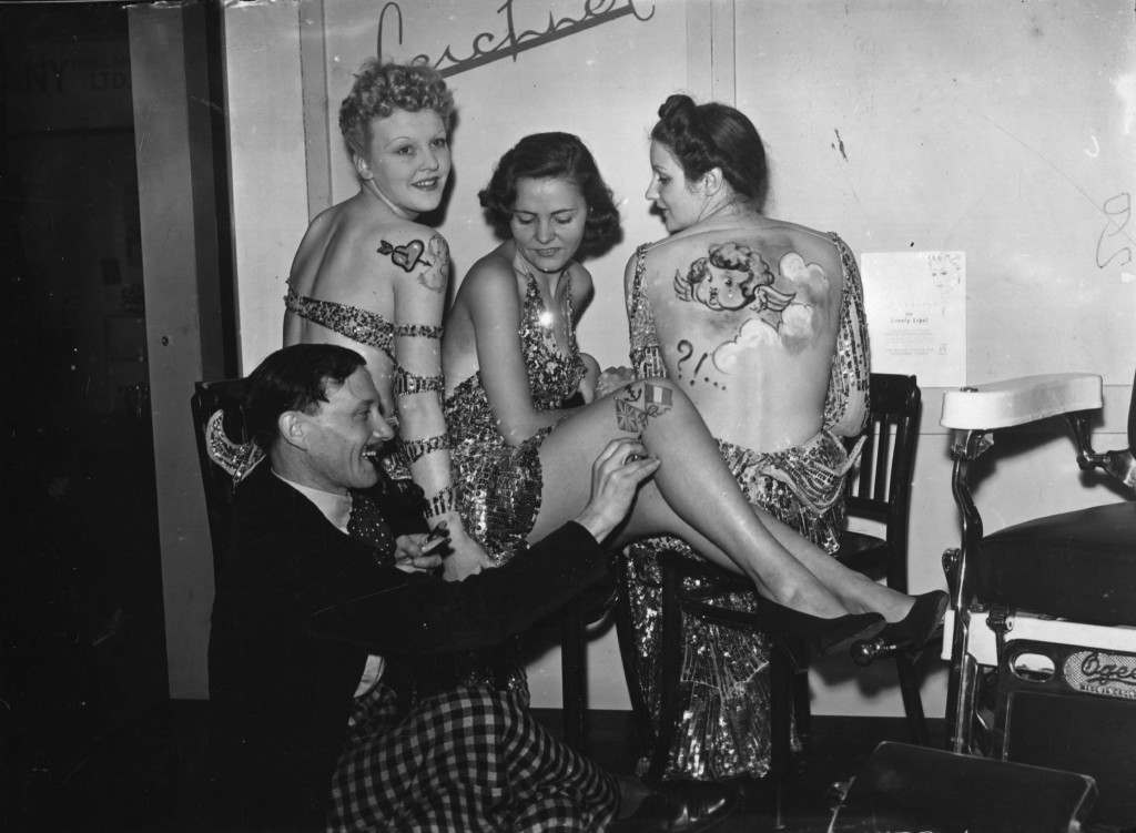 An artist creating skin motifs for evening wear on models at the Hair and Beauty Fair, Olympia, London. 20th September 1938.