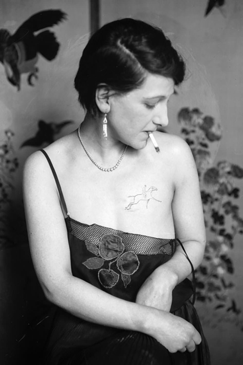 A young woman shows off her chest tattoo of a horse and jockey in 1930.