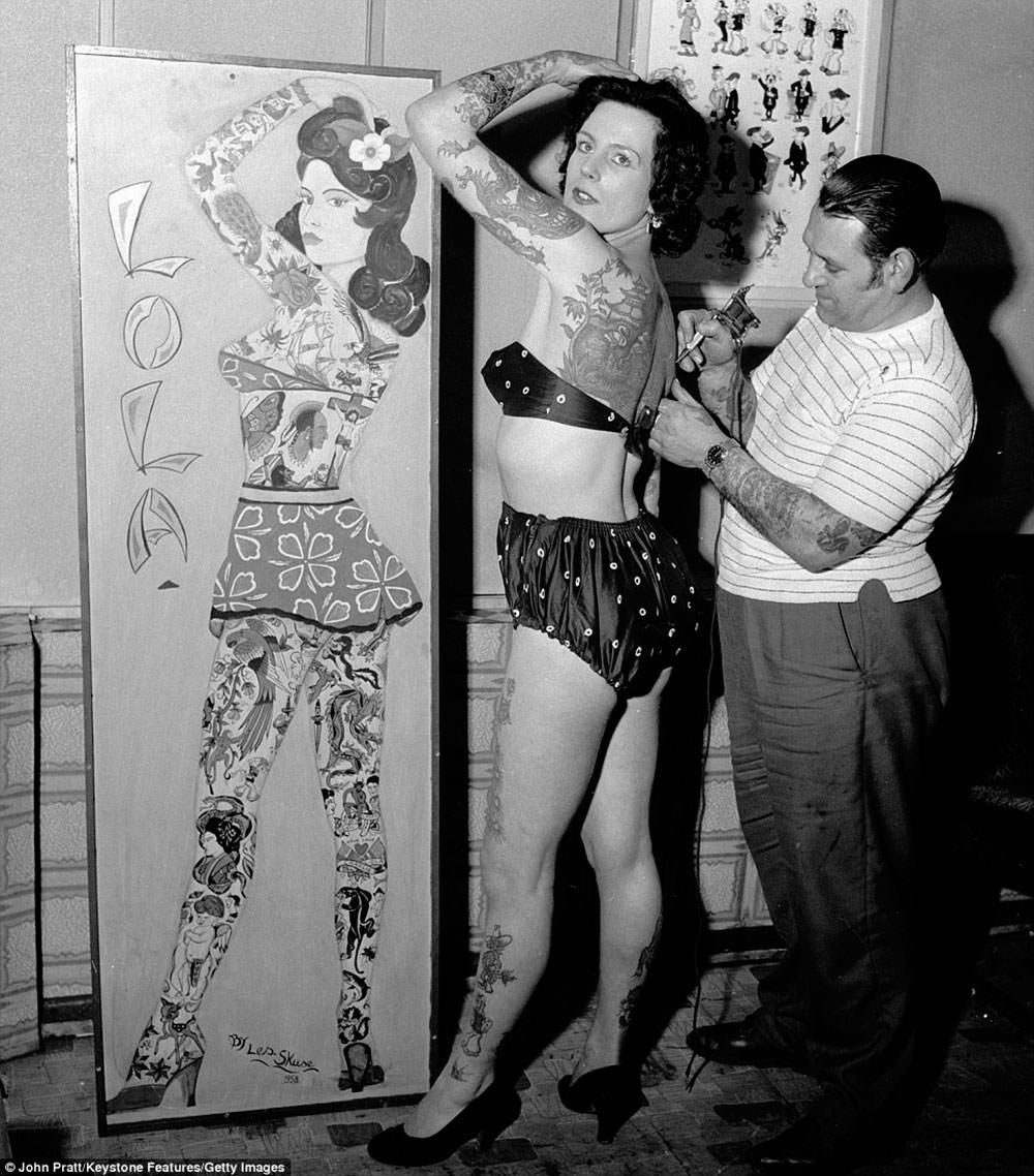 Tattooist Les Skuse at work on tattooed beauty Pam Nash, ca. 1960s.
