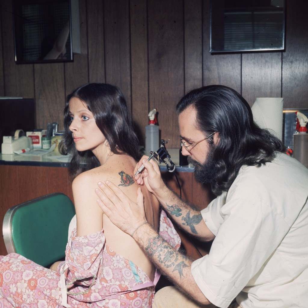 An American tattoo artist working on a client’s shoulder, 1973.