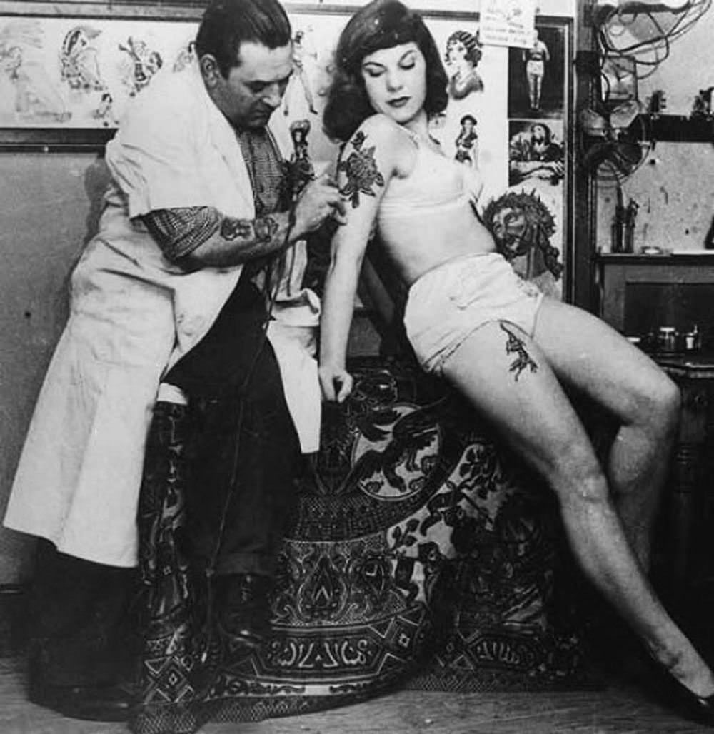 An unidentified Japanese tattoo artist works on a woman's backside, ca. 1930s.