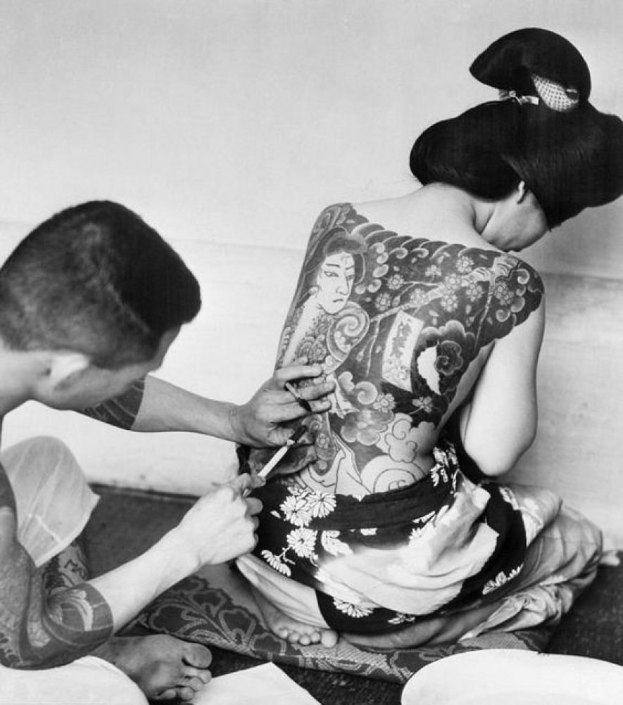 A woman lays her Kimono down as she gets a traditional Japanese tattoo, ca. 1930s.