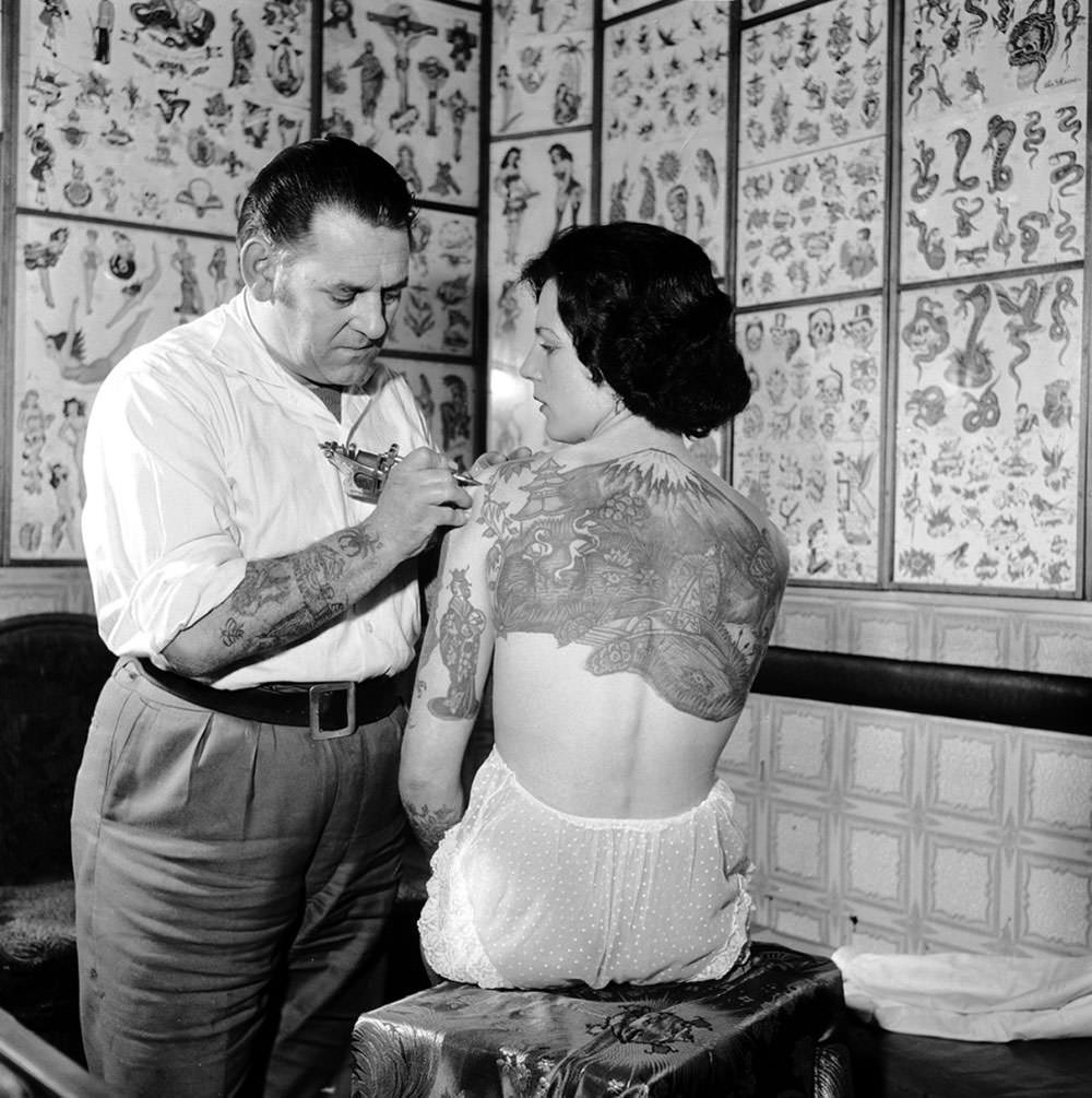 Tattooist Les Skuse works on a large Japanese scene across the back of a client in 1960.