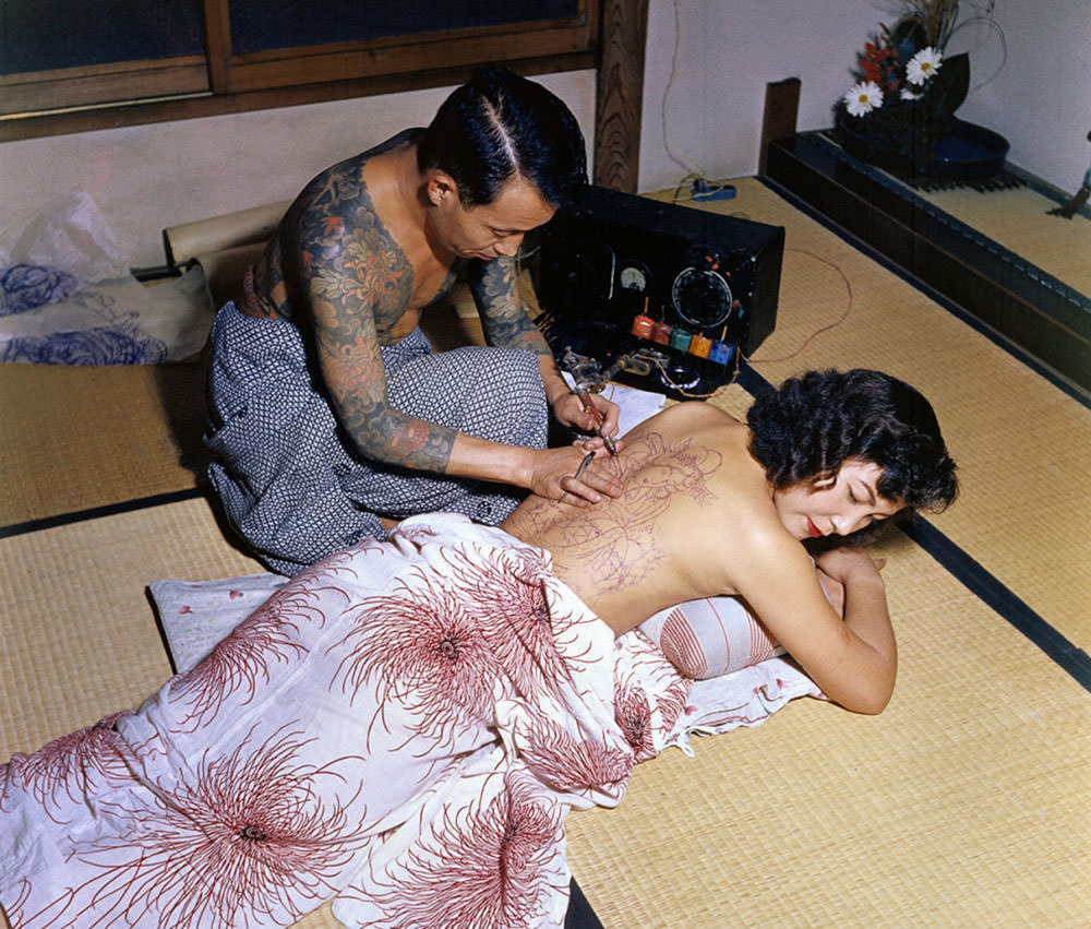 Japanese tattoo artist Tokumitsu Uchida works over the outline of a design during the 1950s.