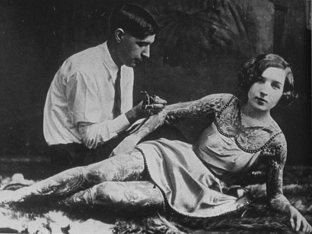 Deafy Grassman tattooing his wife, Stella, ca. 1930s.