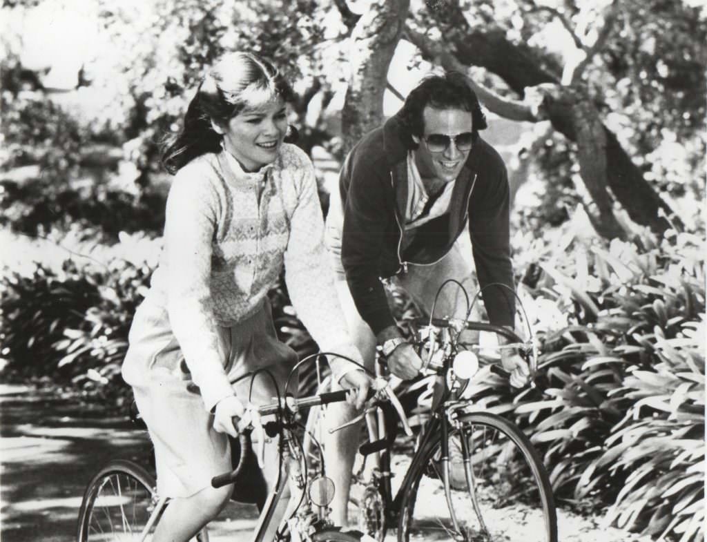 Joan Blondell and Dick Powell riding bikes.