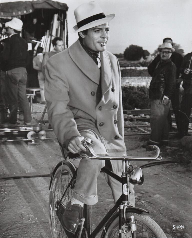 Marcello Mastroianni riding a bike, and smoking a cigarette.