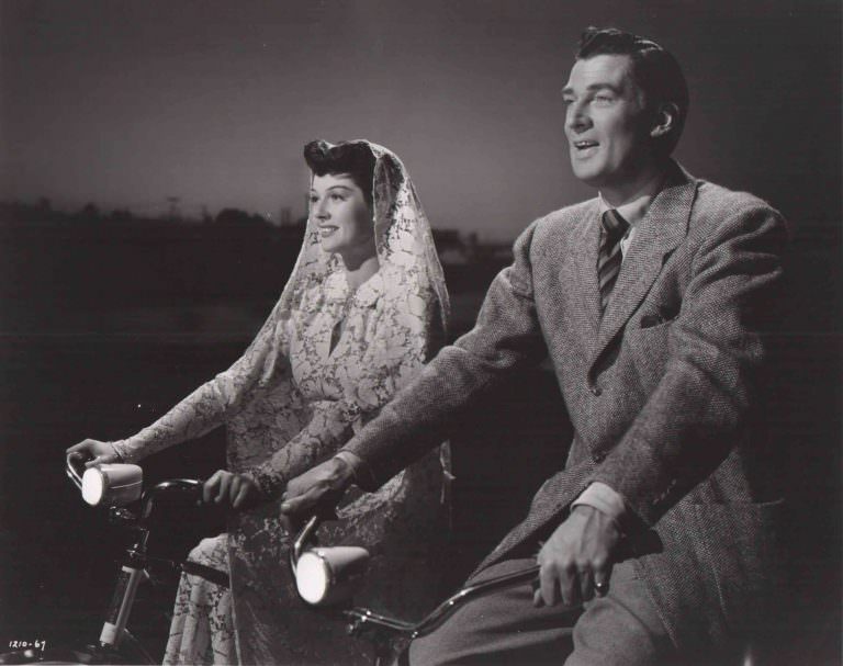 Rosalind Russell and Walter Pidgeon riding bikes.