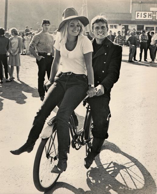 John Phillip Law and Andrea Dromm ride a bike.