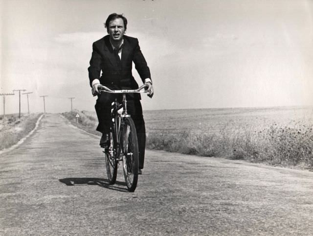 Jean-Louis Trintignant riding a bike.