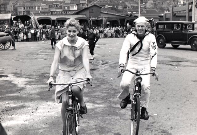 Candice Bergen and Steve McQueen riding bikes.