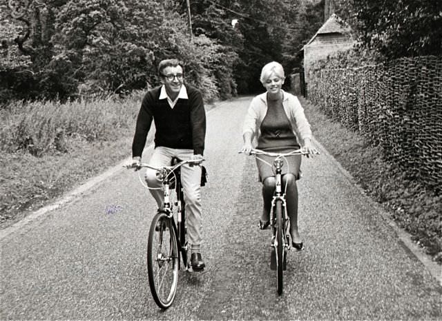 Peter Sellers and Britt Ekland ride bikes.