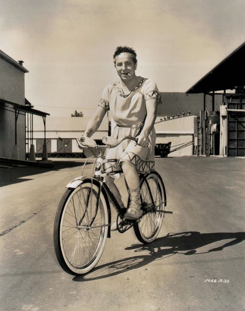 Joe Penner riding a bike, smokes a cigarette, wears a toga.