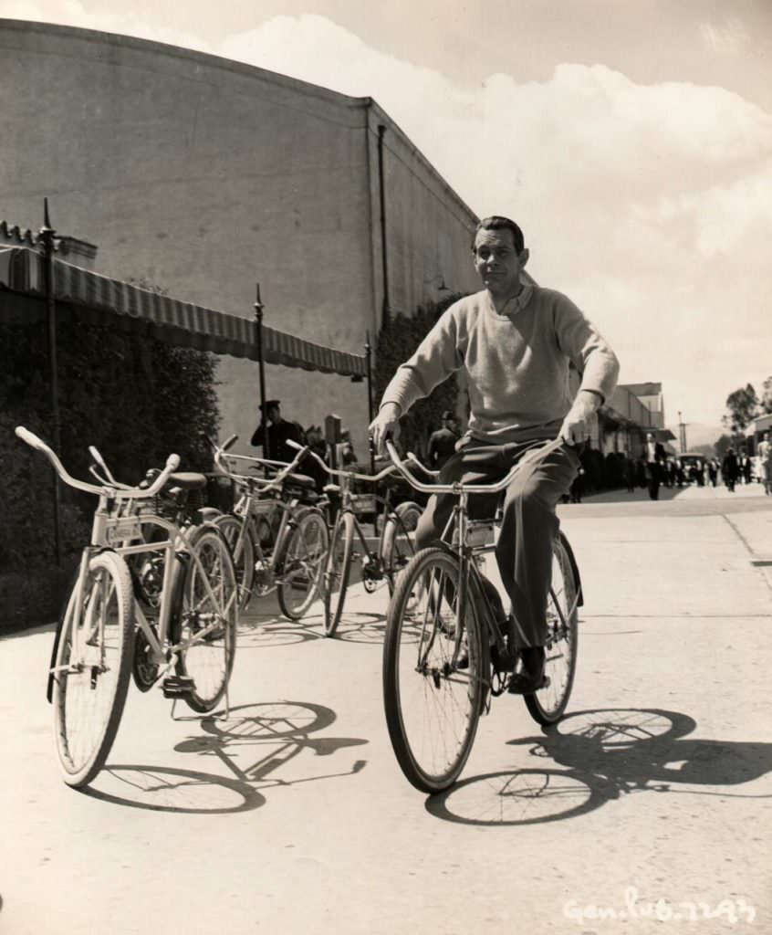 Raymond Massey riding a bike.