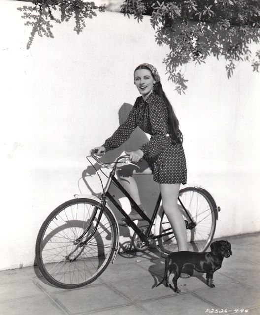 Patricia Morison riding a bike.
