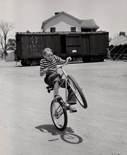 Claude Jarman Jr. wheelies a bike.