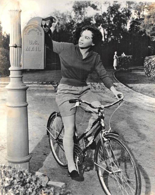 Leslie Caron riding a bike, mails a letter