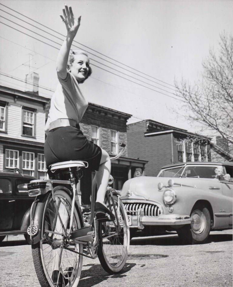 Jan Sterling riding bike, waves goodbye.