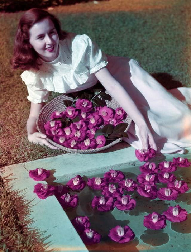 Woman posing with camellias at Killearn Gardens State Park in Tallahassee, circa 1955
