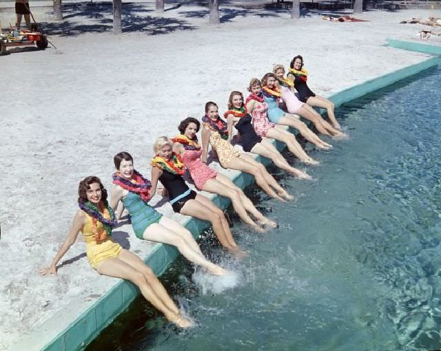 Women wearing leis posing in bathing suits at the beach, circa 1955