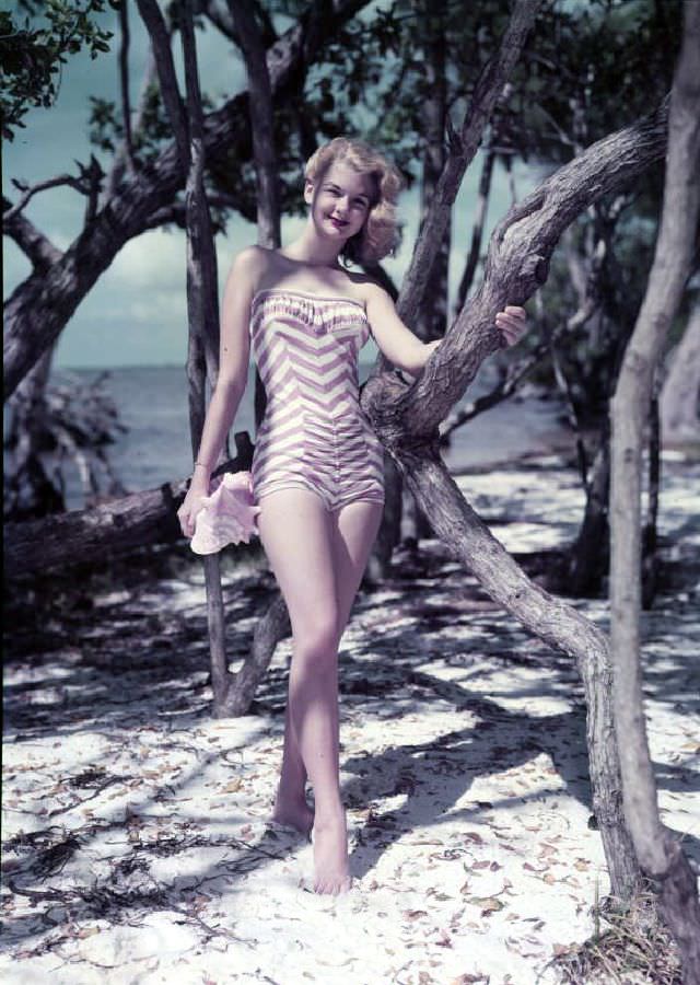 Model on the beach with sea shell, Florida, circa 1959