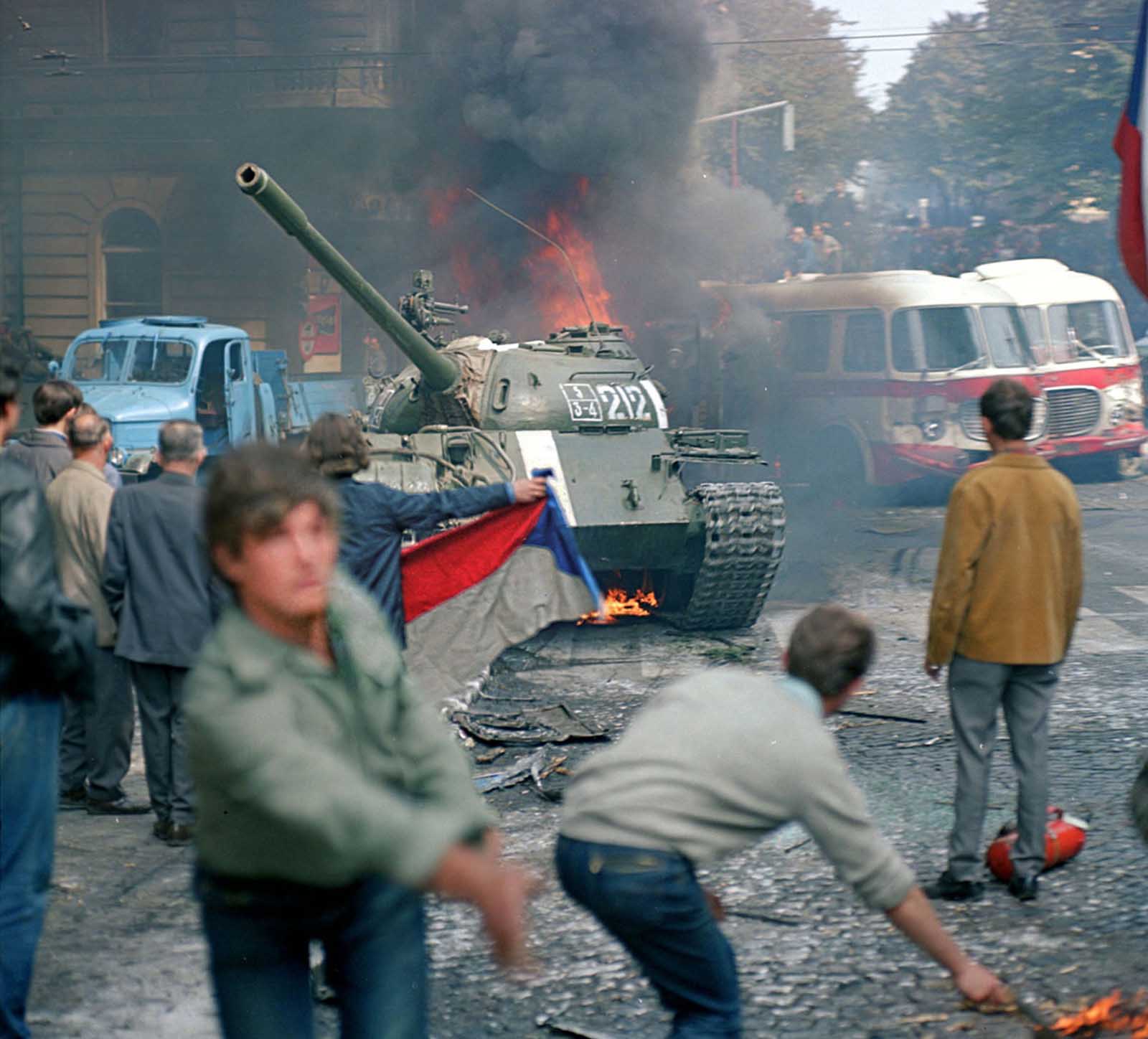 Prague residents, carrying a Czechoslovakian flag and throwing Molotov cocktails, attempt to stop a Soviet tank in downtown Prague on August 21, 1968.