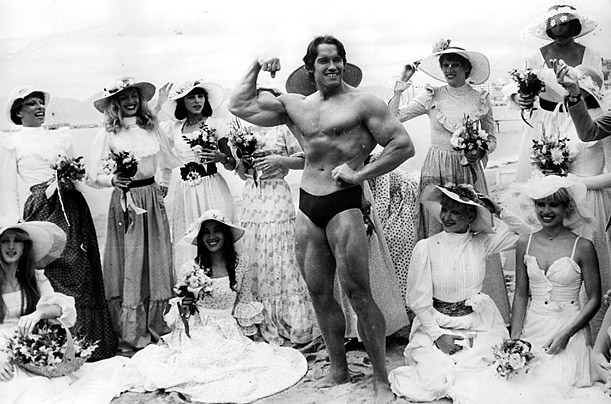 Arnold Schwarzenegger, the film actor who first became famous as Mr Universe for his magnificent physique, on Cannes beach during the Film Festival with the girls from the Folies Bergere.