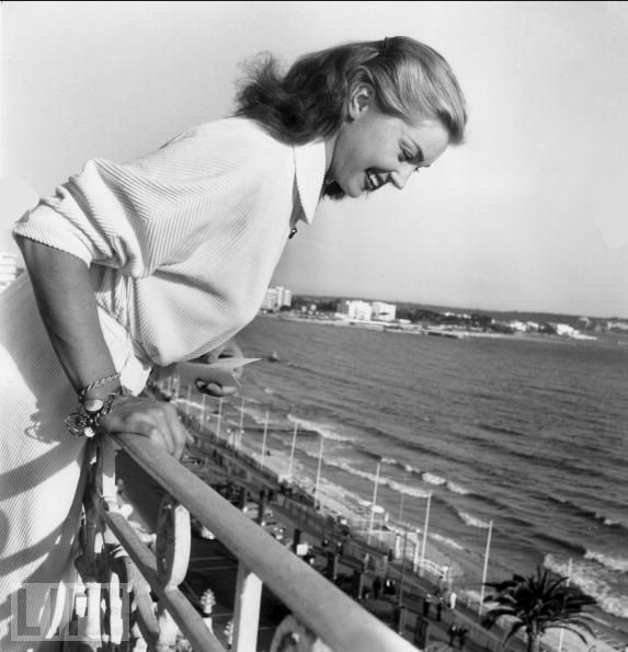 Esther Williams, famous for her swimming movies, throws autographs off a balcony to her fans during the Cannes Film Festival on April 27, 1955.