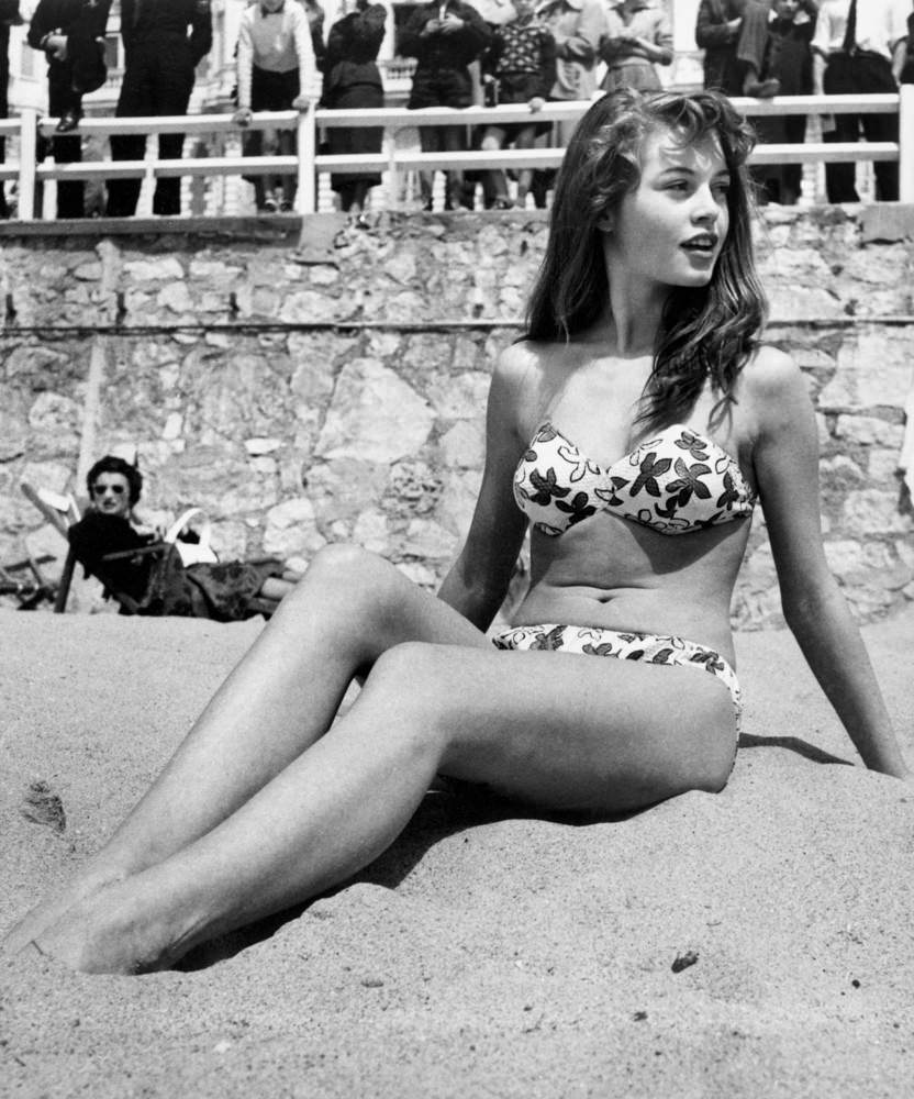 French actress Brigitte Bardot sitting on the beach during the Cannes Film Festival, 1953.
