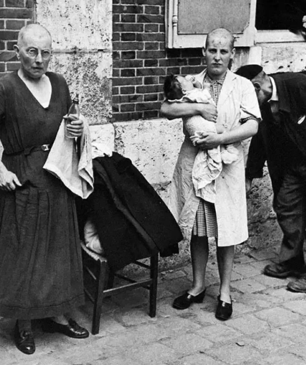 A Frenchwoman collaborator and her baby with her mother followed by a throng of taunting townspeople in August 1944.