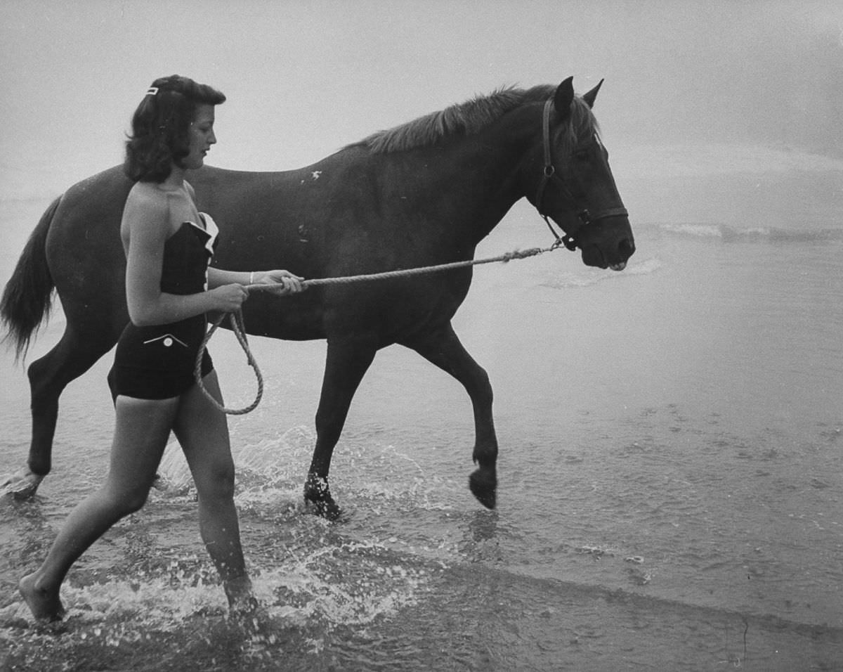 A woman walks a diving horse on the beach at Atlantic City, New Jersey, 1953