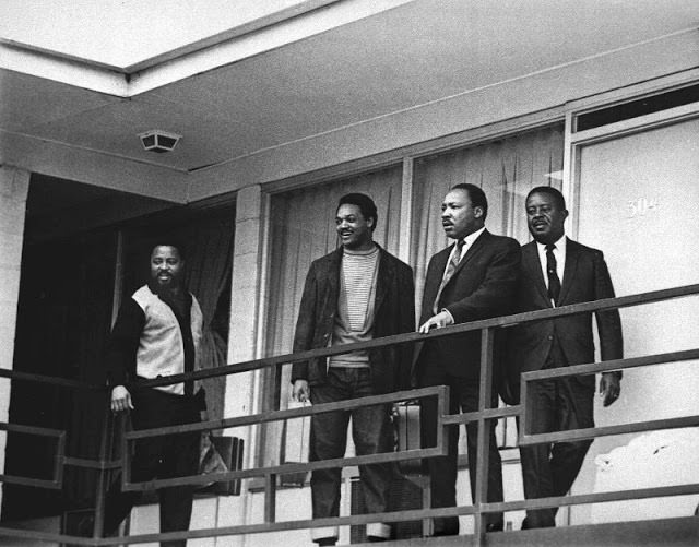 Martin Luther King standing on the balcony on the day of his assassination along with his best friend Ralph Abernathy on the right. On the left is Jesse Jackson, to his left another preacher.