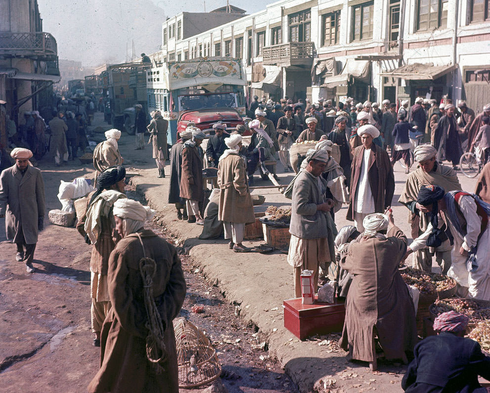 Men stroll past roadside vendors as a painted truck makes its way through the busy street in Kabul, Afghanistan, November, 1961.