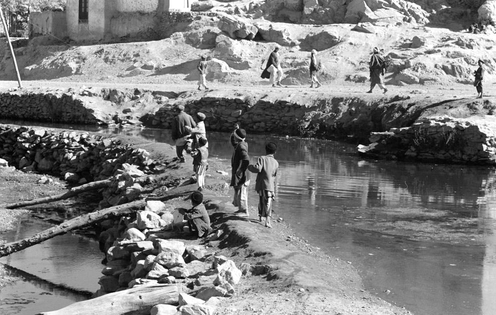 Afghan boys play with kites as men walk past, in November of 1959.