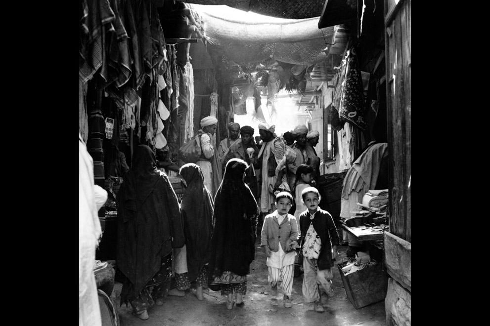 Afghan boys, men, and women, some in bare feet, shop at a marketplace in Kabul, Afghanistan, in May of 1964.
