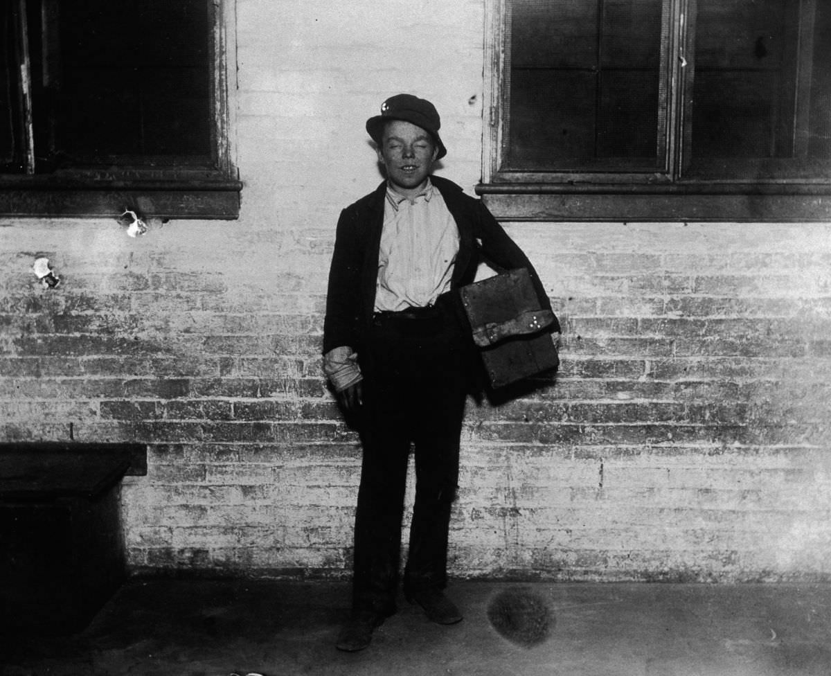 A shoeshine boy named Tommy holds his shoeshine kit on a sidewalk, 1890